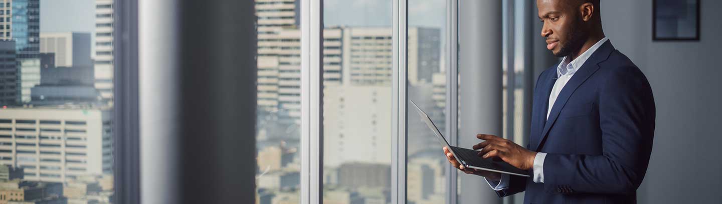 Image depicting a businessman standing at a window in an office building