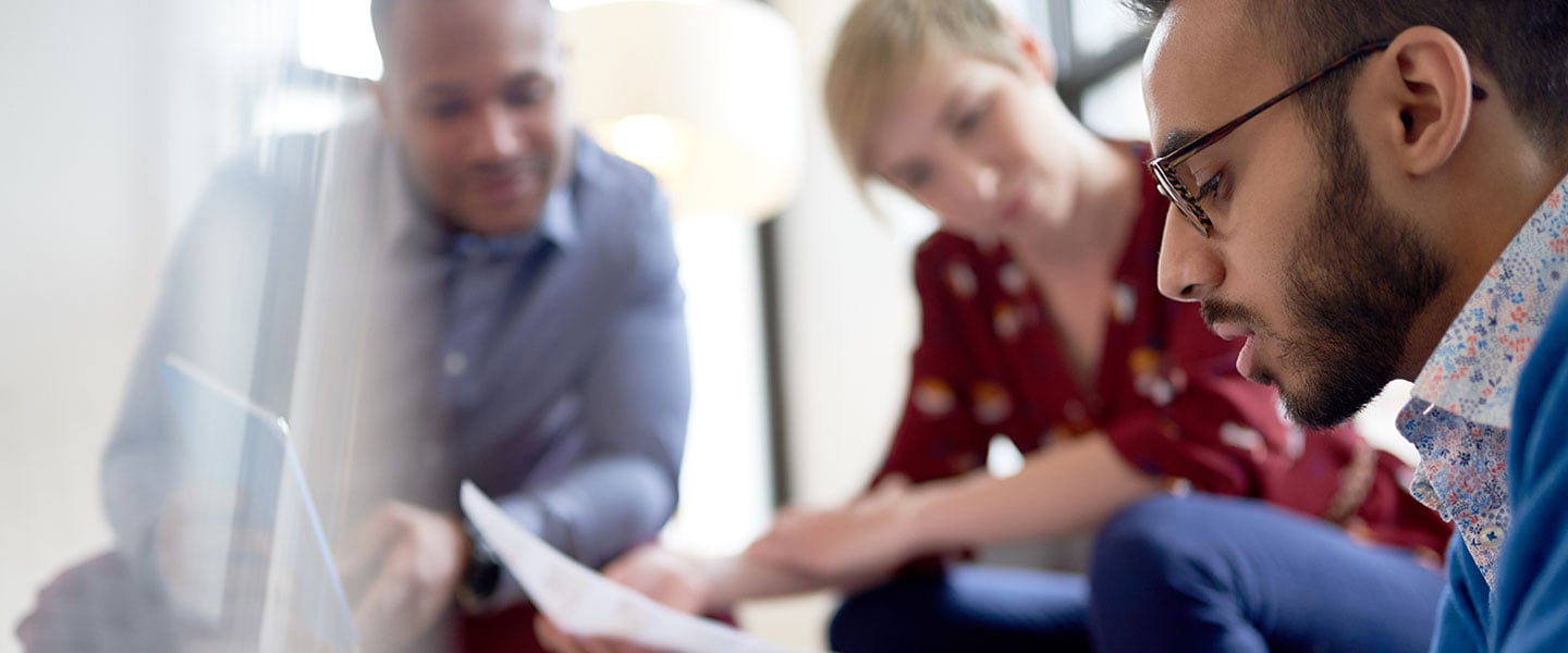 Three people discussing and looking at a piece of paper